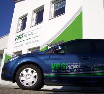 VBG Verkehrsbildungsgesellschaft Auto mit VBG-Beschriftung vor Piendl-Firmengebäude